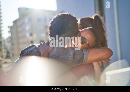 Happy young couple hugging on sunny urban balcony Stock Photo