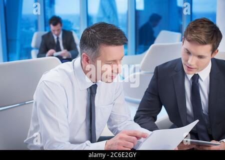 Businessmen reviewing paperwork in office Stock Photo