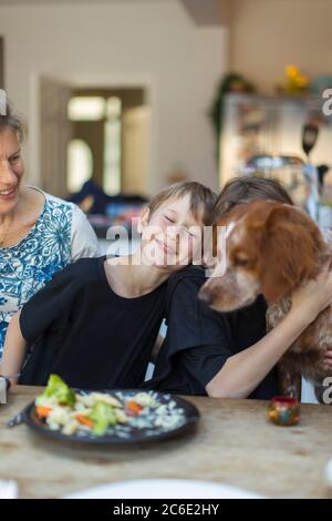Happy family with dog eating lunch at dining table Stock Photo