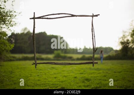 Branch frame over woman walking in idyllic grass field Stock Photo
