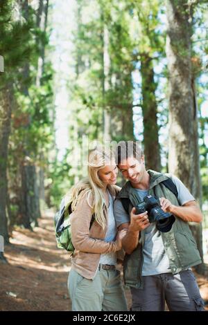 Smiling couple looking at digital camera in woods Stock Photo