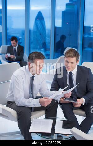Businessmen reviewing paperwork in office Stock Photo