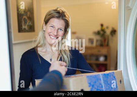 Portrait smiling woman receiving delivery at front door Stock Photo