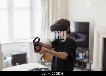 Boy playing video game with VRS goggles in living room Stock Photo