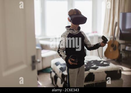 Boy playing video game with VRS goggles in living room Stock Photo