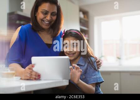 Happy mother and daughter using digital tablet in kitchen Stock Photo