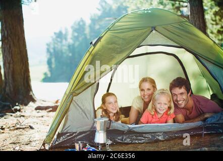 Smiling family inside of tent in woods Stock Photo