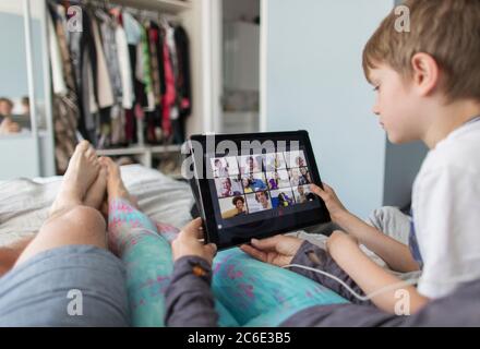 POV family with digital tablet video chatting with friends on bed