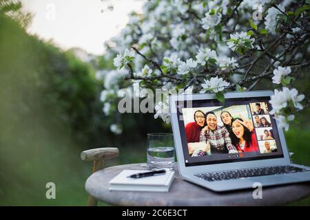 Happy friends video chatting on laptop screen in garden Stock Photo