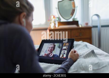 Woman with digital tablet video chatting on bed Stock Photo
