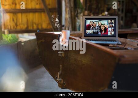 Friends video chatting on laptop screen on wooden boat Stock Photo