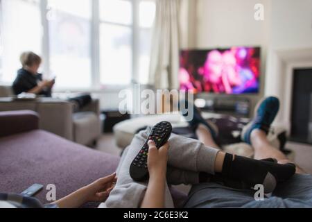 POV family with remote control watching TV in living room Stock Photo
