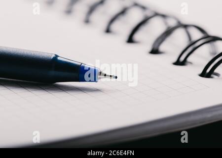 Opened notepad in a cage with an automatic plastic ballpoint pen close-up. Stock Photo