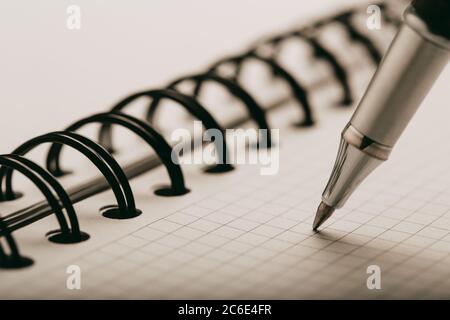 Opened notepad in a cage with an automatic plastic ballpoint pen close-up. Stock Photo