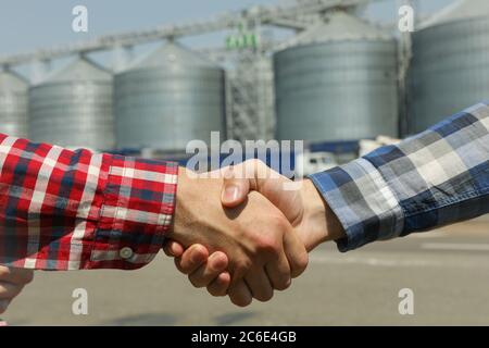 Businessmen shake hands against silos. Agriculture business Stock Photo