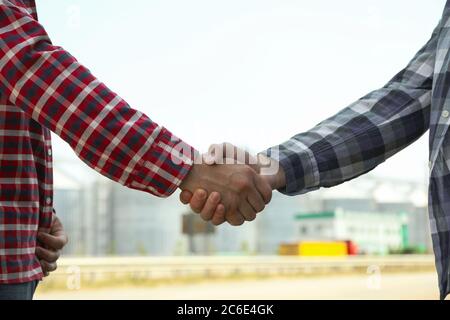 Businessmen shake hands against silos. Agriculture business Stock Photo