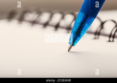 Opened notepad in a cage with an automatic plastic ballpoint pen close-up. Stock Photo