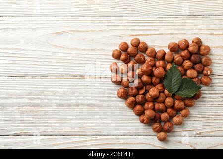 Heart made of hazelnuts on wooden background, top view Stock Photo