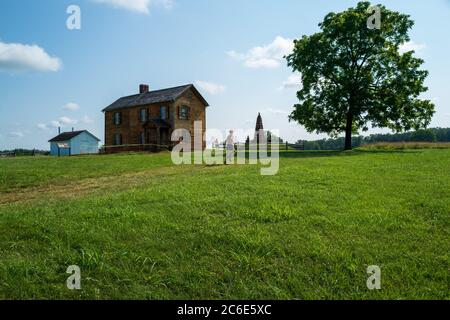 Manassas, VA, USA -- July 8, 2020. A wide angle photo with a man jogging  past the Stone House on a Manassas battlefield trail. Stock Photo