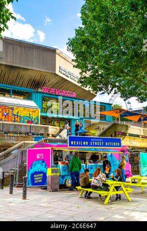 People eating outdoors at Wahaca restaurant Mexican food stall at the Southbank Centre Queen Elizabeth Hall building, Southbank, London, UK