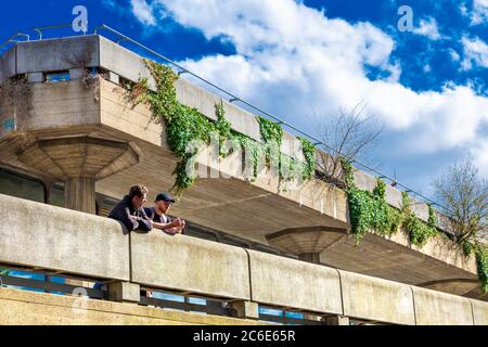 Two men talking on the terrace of brutalist style Queen Elizabeth Hall in Southbank Centre, Southbank, London, UK Stock Photo