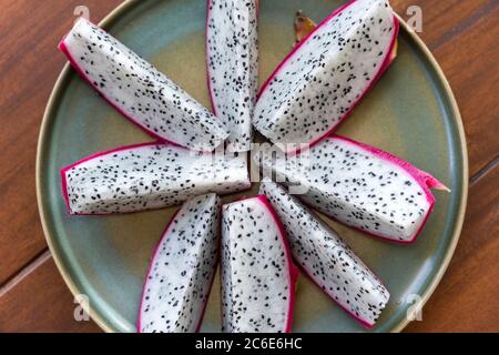 Sliced ripe dragon fruit on plate background. Pitaya or pitahaya. Top view, close up Stock Photo