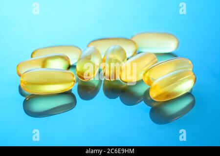 Omega 3 capsules on the gloss surface with reflections. Some fish oil capsules, close up macro. Stock Photo