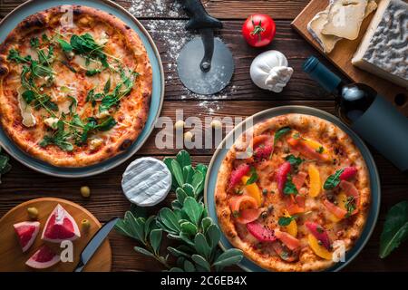 Two pizza on platters which is on wooden background, top view and copy space. One pizza with cheese, anothe pizza with fish and grapefruit. Stock Photo