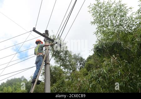 Huangshan, China's Anhui Province. 9th July, 2020. An electrician repairs electric wires in Zhangcun Village of Huizhou District in Huangshan City, east China's Anhui Province, July 9, 2020. Heavy rainfall hit the Huizhou District of Huangshan City, leaving several villages inundated in varying degrees. The local authorities rapidly organized flood response efforts to evacuate effected residents, rehabilitate destroyed roads and dredge silt-clogged ditches. Credit: Han Xiaoyu/Xinhua/Alamy Live News Stock Photo