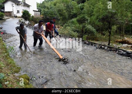 Huangshan, China's Anhui Province. 9th July, 2020. Villagers clean a flooded road in Zhangcun Village of Huizhou District in Huangshan City, east China's Anhui Province, July 9, 2020. Heavy rainfall hit the Huizhou District of Huangshan City, leaving several villages inundated in varying degrees. The local authorities rapidly organized flood response efforts to evacuate effected residents, rehabilitate destroyed roads and dredge silt-clogged ditches. Credit: Zhou Mu/Xinhua/Alamy Live News Stock Photo