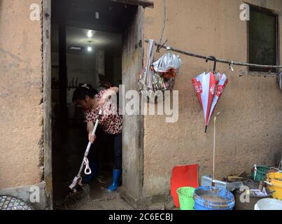 Huangshan, China's Anhui Province. 8th July, 2020. A villager clears away the silt at her home in Zhangcun Village of Huizhou District in Huangshan City, east China's Anhui Province, July 8, 2020. Heavy rainfall hit the Huizhou District of Huangshan City, leaving several villages inundated in varying degrees. The local authorities rapidly organized flood response efforts to evacuate effected residents, rehabilitate destroyed roads and dredge silt-clogged ditches. Credit: Han Xiaoyu/Xinhua/Alamy Live News Stock Photo