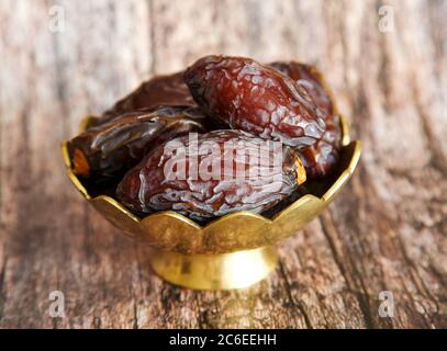 Royal large dates Medjool  in a golden bowl on a wooden background Stock Photo