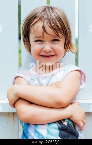 Portrait of blond-haired girl with arms crossed smiling Stock Photo