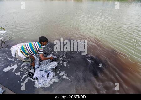Tongi, Bangladesh. 9th July, 2020. A Bangladeshi man washes plastic waste, which were used to carry chemicals, in the water of the Turag River before recycling it, in Tongi, near Dhaka, Bangladesh, July 9, 2020. Credit: Suvra Kanti Das/ZUMA Wire/Alamy Live News