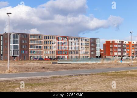 Amsterdam, Netherlands - February 24, 2017: Colorful facades of living houses standing in a row under blue cloudy sky Stock Photo