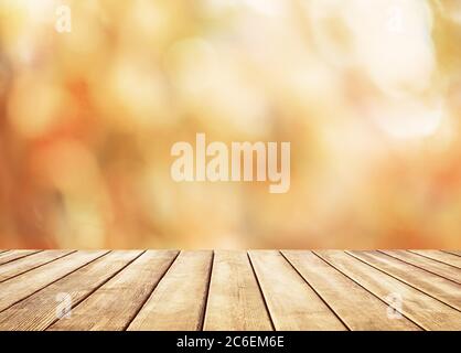 Wooden table top on blur abstract autumn background. Autumn golden abstract background with bokeh light. Stock Photo