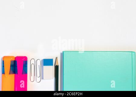 Office or school related objects on a white background: notebooks, highlighters, rubber, pencil, clips Stock Photo