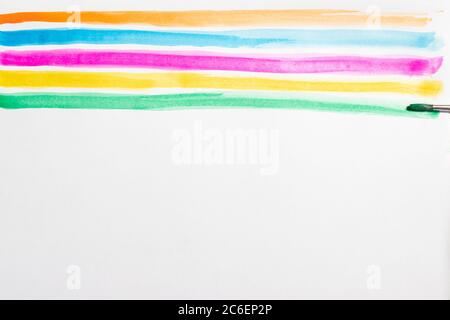 Brush making colorful lines with watercolors on a white background, copy space Stock Photo