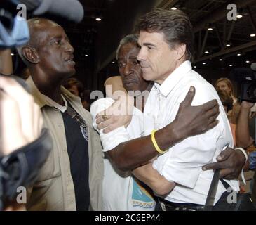 Austin, Texas USA, September 5, 2005:  Texas Governor Rick Perry (right) hugs a Hurricane Katrina refugee from New Orleans at the Austin Convention Center as he toured facilities statewide that are helping house the estimated 200,000 evacuees in Texas. ©Bob Daemmrich Stock Photo