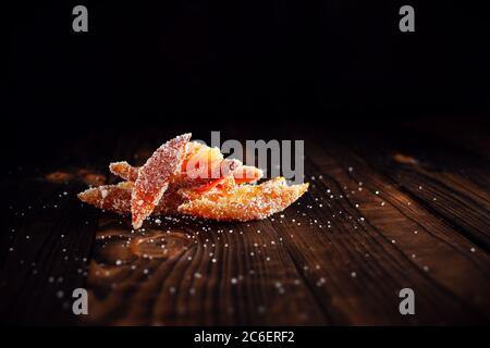 Orange peels in sugar. Candied fruit from orange. Orange marmalade on a wooden brown table with a black background. Empty space for text. Stock Photo