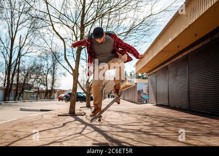 A young hipster male makes a jump with a skateboard, kickflip, or Ollie. Concept of active lifestyle and street culture. Stock Photo