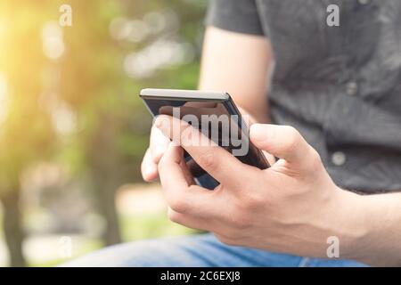 Man using mobile smart phone, close up. Young man holding mobile smart phone. Stock Photo