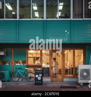 Nagoya, Aichi, Japan - A small bakery cafe in Tsurumai. Woman buying cake and coffee. Ordinary daily life in village. Warm lighting and atmosphere. Stock Photo