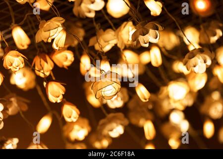 Colored artificial lights shaped like yellow flowers hanging from the ceiling Stock Photo