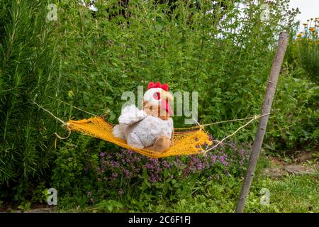 White soft toy lies in a hammock between green bushes in a meadow Stock Photo