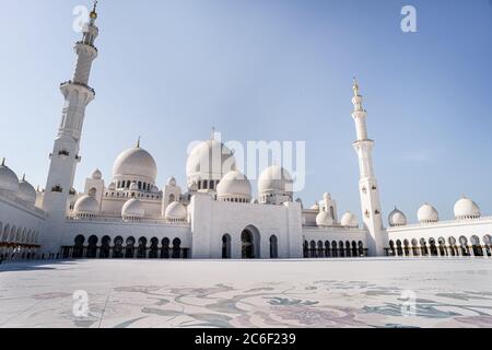 View of the inner courtyard and its domes of the Abu Dhabi mosque during a sunny day with a blue sky Stock Photo