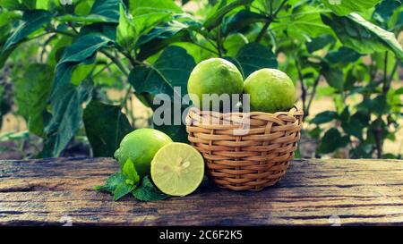 Basket full of lemons and half cut lemon on a wooden table Stock Photo