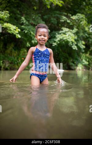 A young girl wades and splashes in the Shenandoah River, Virginia, USA.