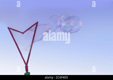 Blowing large soap bubbles using big plastic wand Stock Photo