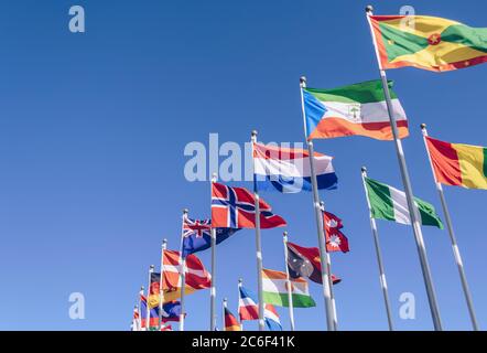 waving in the wind flags of different countries with blue sky on background Stock Photo
